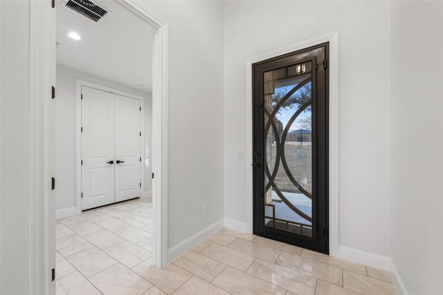Foyer featuring light marble finish floors and baseboards