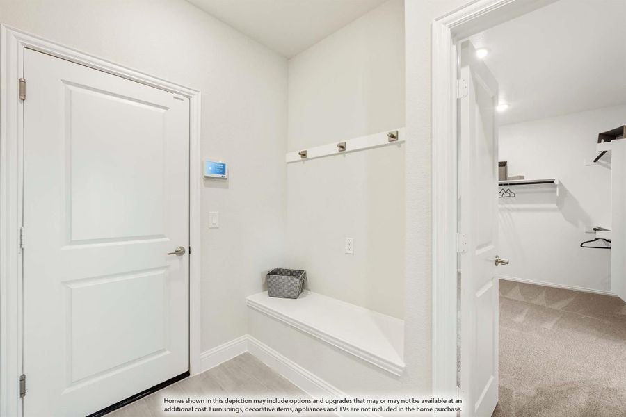 Mudroom with built-in bench, coat hooks, and doorway leading to a walk-in closet with shelving