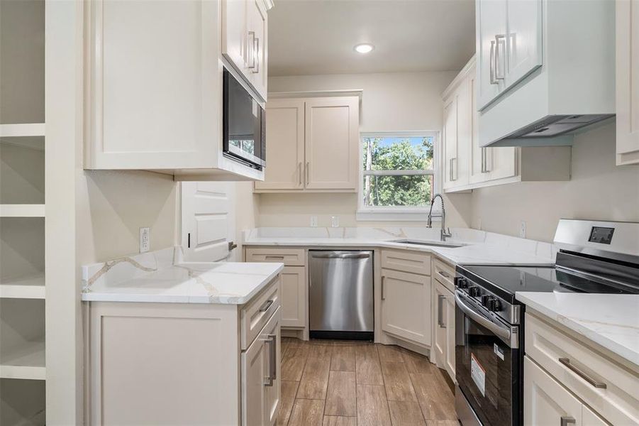 Modern kitchen featuring light-toned cabinetry, stainless steel appliances, white countertops, and wood-finish flooring Modern kitchen featuring light-toned cabinetry, stainless steel appliances, white countertops, and wood-finish flooring