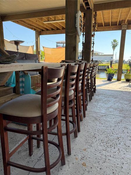 This photo showcases  a long wooden bar table and high-backed chairs, ideal for entertaining.  Perfect for enjoying scenic surroundings and leisurely gatherings.