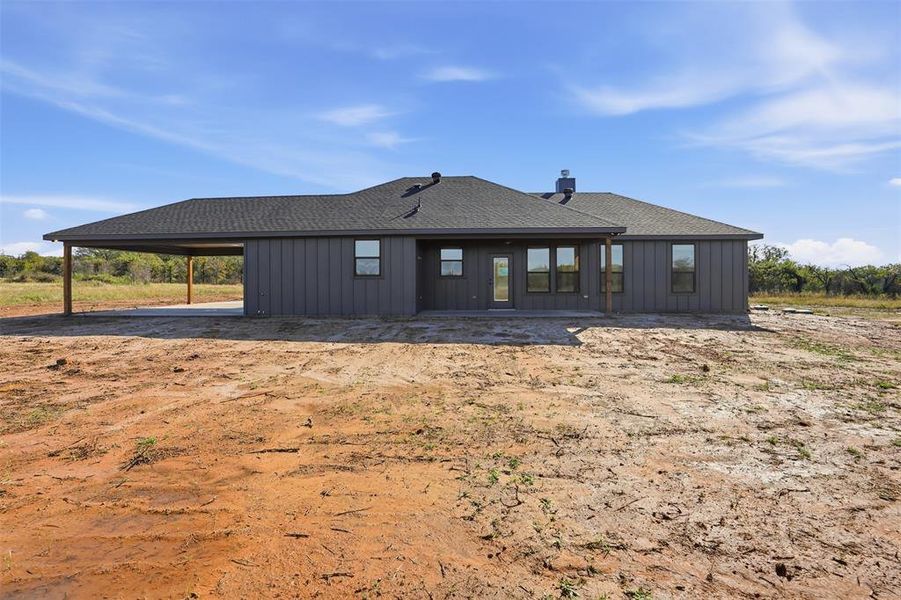 Rear view of property with roof with shingles, board and batten siding, a patio, and an attached carport Rear view of property with roof with shingles, board and batten siding, a patio, and an attached carport