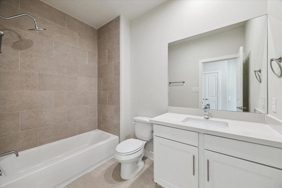 Earth-toned floor-to-ceiling tilework in the shower pairs beautifully with a sleek white quartz vanity to create a calm, spa-like atmosphere for relaxation.