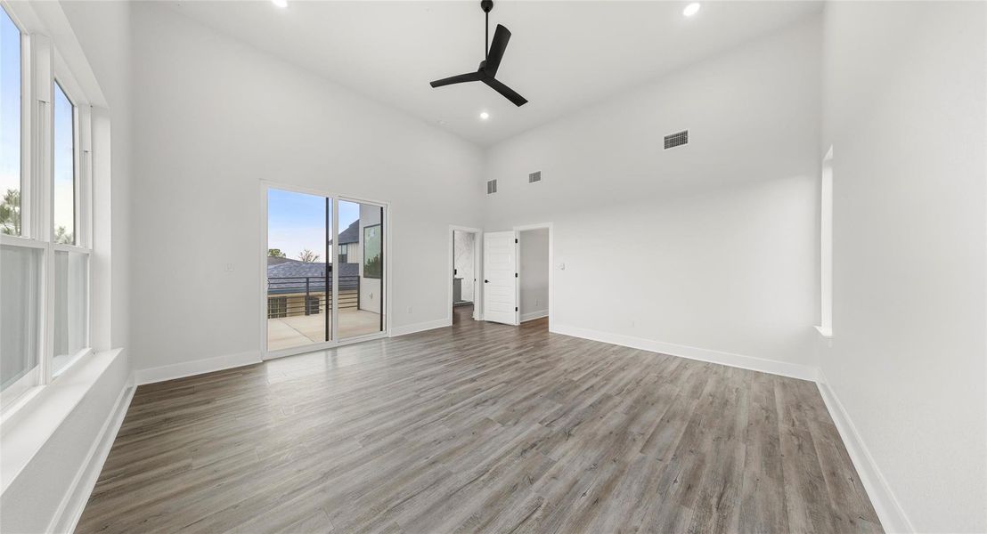 Unfurnished bedroom with a towering ceiling, ceiling fan, access to outside, light wood finished floors, and recessed lighting