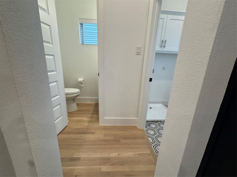 Bathroom featuring baseboards, toilet, and wood finished floors