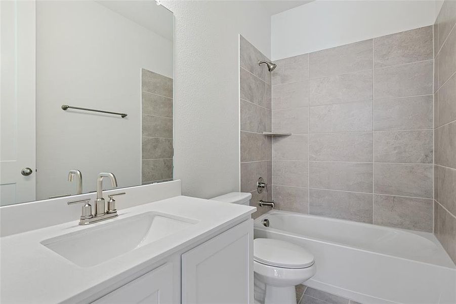 Full bathroom featuring tiled shower / bath combo, vanity, and toilet Full bathroom featuring tiled shower / bath combo, vanity, and toilet