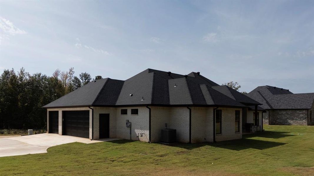 View of property exterior featuring a yard, driveway, a garage, and brick siding View of property exterior featuring a yard, driveway, a garage, and brick siding