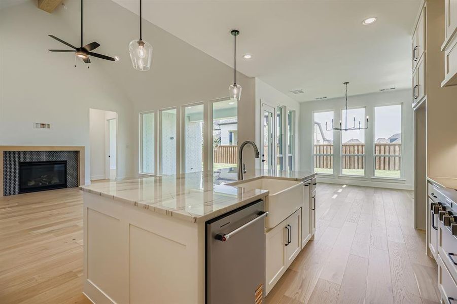 Kitchen with open floor plan, light wood finished floors, dishwasher, a chandelier, and beamed ceiling