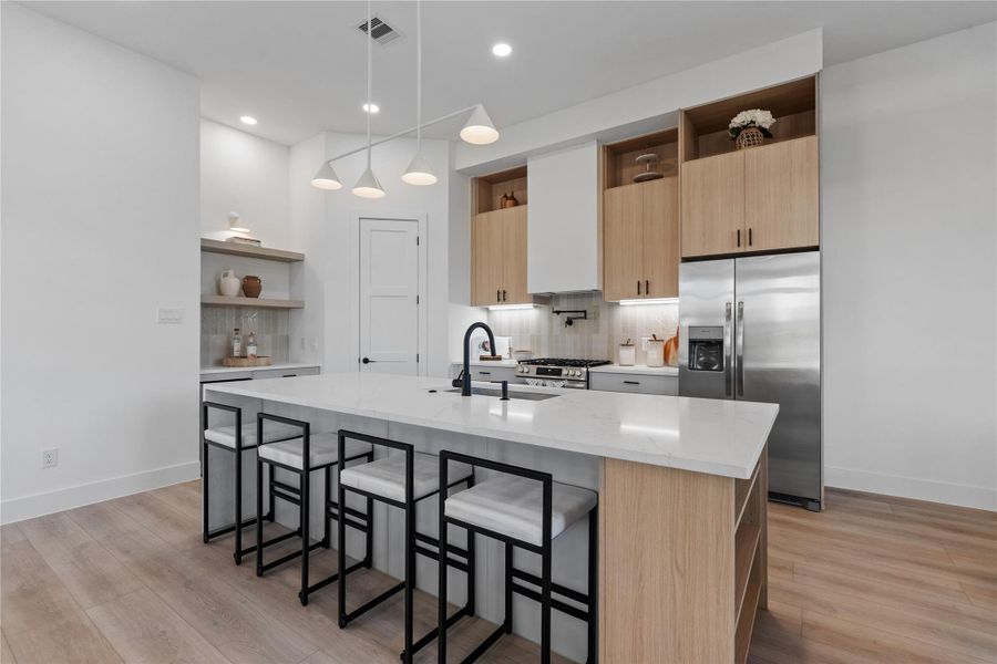 Layered cabinetry and open shelving create depth and contrast, while the layout prioritizes clear workflow and intuitive movement throughout the space.