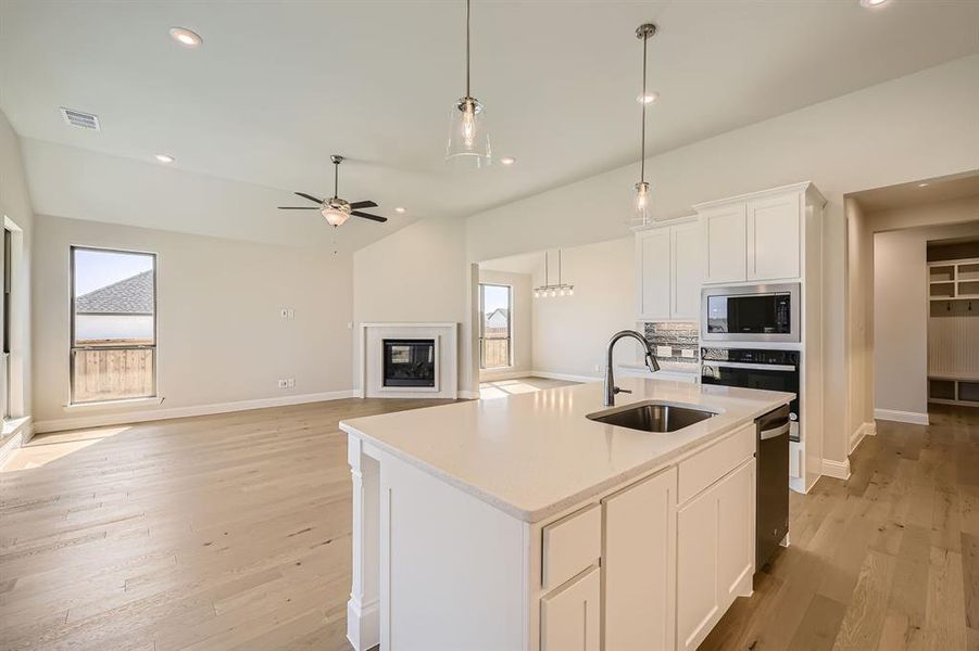 Kitchen featuring an island with sink, lofted ceiling, sink, white cabinetry, and appliances with stainless steel finishes