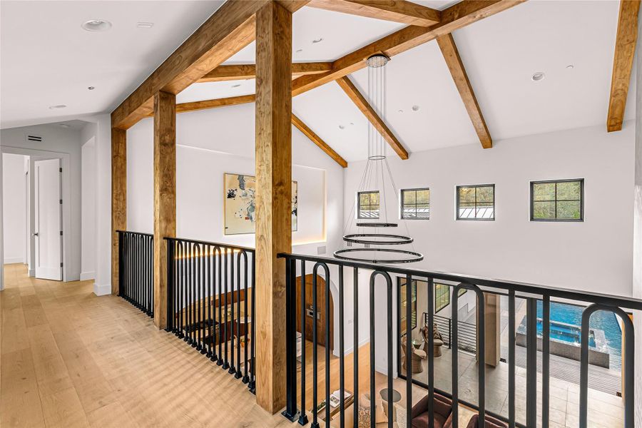 A spacious room offers vaulted ceilings, sleek recessed lighting, and rich hardwood flooring.