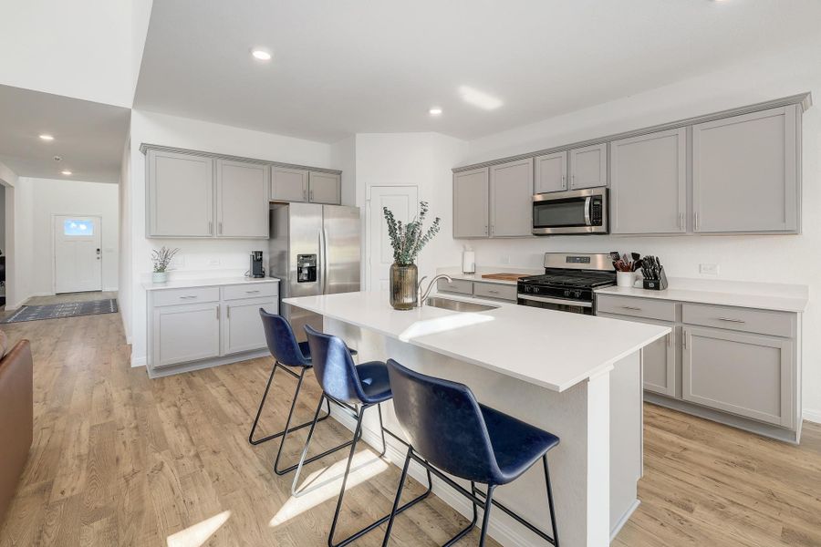Kitchen featuring a center island with countertop seating, light wood-finish flooring, stainless steel appliances, light gray cabinetry, and recessed lighting Kitchen featuring a center island with countertop seating, light wood-finish flooring, stainless steel appliances, light gray cabinetry, and recessed lighting