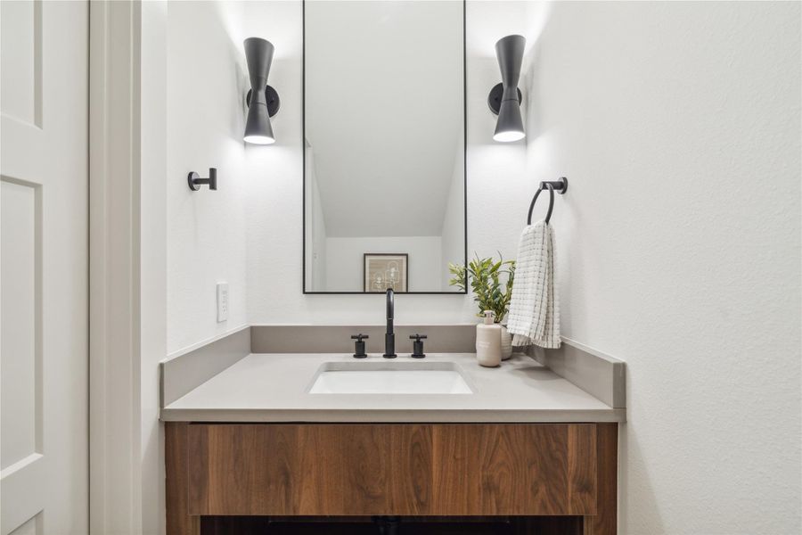 Contrasting finishes and statement lighting elevate the powder room, offering a warm, designer-inspired moment in a compact space.