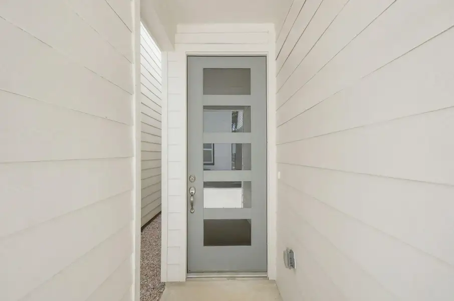 Modern front entry featuring a contemporary glass-panel door, clean architectural details, and exterior lighting. Modern front entry featuring a contemporary glass-panel door, clean architectural details, and exterior lighting.
