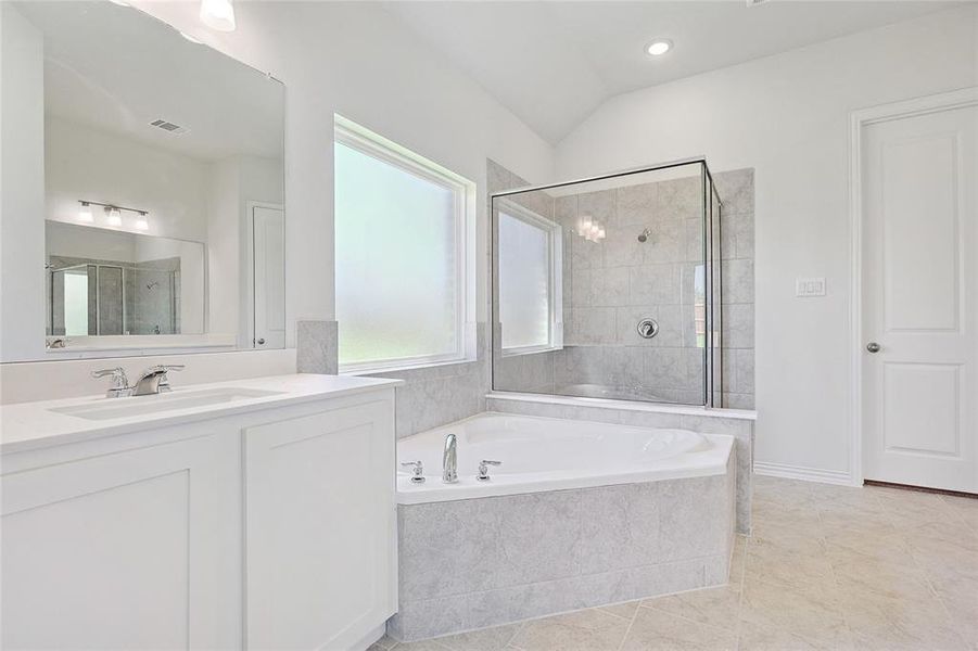 Bathroom featuring tile patterned flooring, vaulted ceiling, vanity, and plus walk in shower