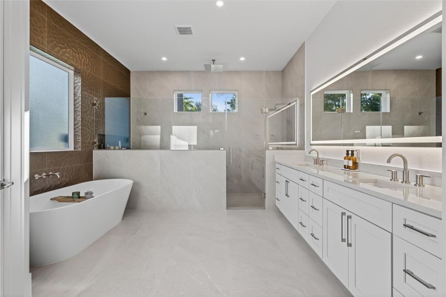 Spa-inspired primary bathroom features dual vanities, a freestanding soaking tub, oversized shower, and elegant modern finishes. **Images are from a previously completed project. **