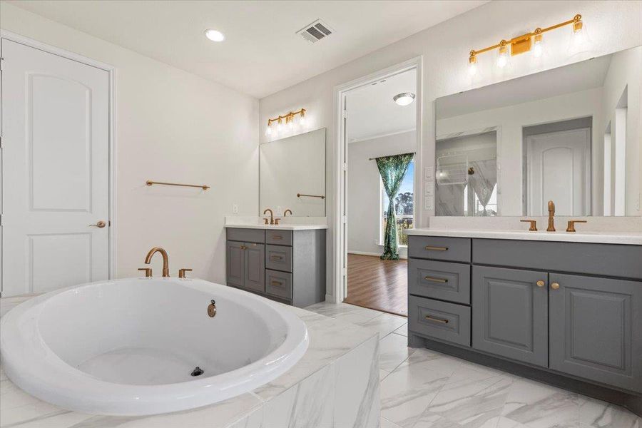Bathroom with two vanities, tiled tub, recessed lighting, light marble finish flooring, and a shower stall Bathroom with two vanities, tiled tub, recessed lighting, light marble finish flooring, and a shower stall