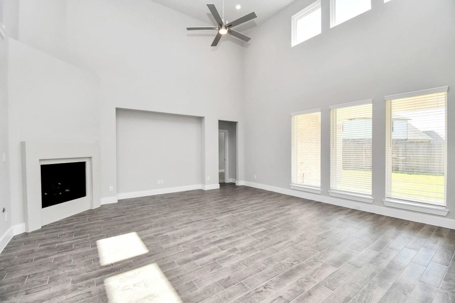 Welcome family and guests to your charming living room! With its high ceilings, recessed lighting, ceiling fan, custom paint, beautiful flooring, and large windows that let in abundant natural light, this room is perfect for gatherings. Sample photo of completed home with similar floor plan. Actual colors and selections may vary.