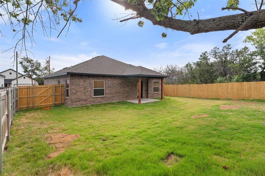 Back of house with a fenced backyard, brick siding, a patio area, roof with shingles, and a gate