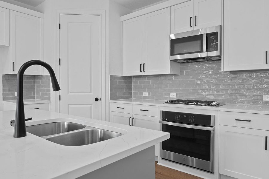 Kitchen with stainless steel appliances, white cabinetry, light stone countertops, and tasteful backsplash Kitchen with stainless steel appliances, white cabinetry, light stone countertops, and tasteful backsplash