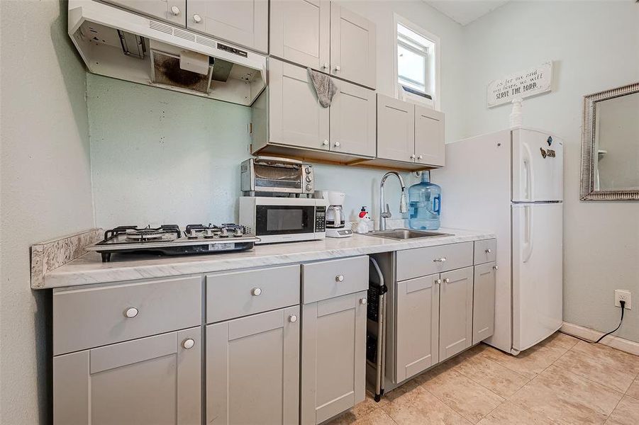 There is an exhaust hood positioned above the stove, ensuring efficient ventilation and odor removal during cooking.