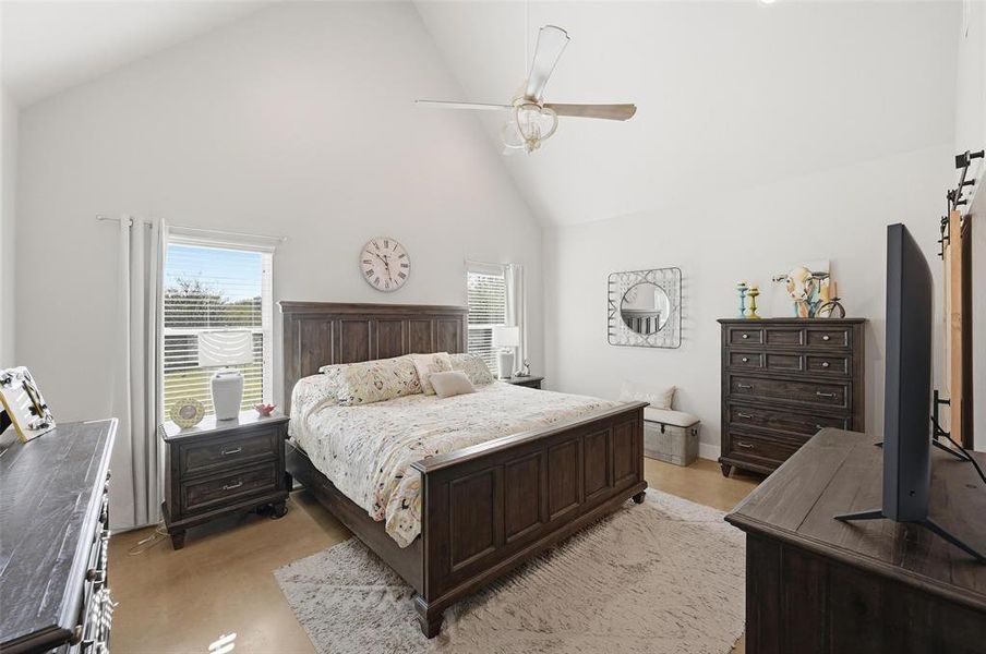 Bedroom featuring high vaulted ceiling, ceiling fan, and a barn door Bedroom featuring high vaulted ceiling, ceiling fan, and a barn door