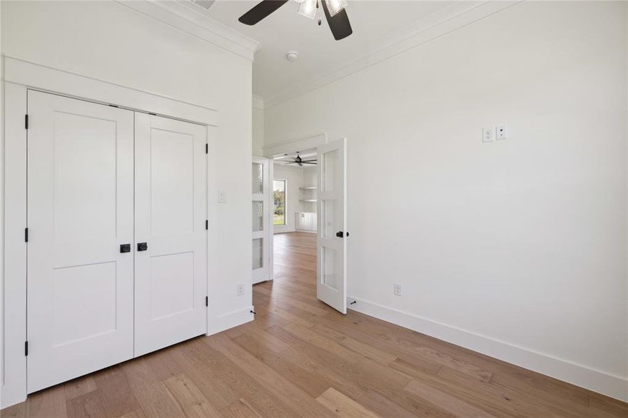 Unfurnished bedroom featuring a closet, ceiling fan, crown molding, and light wood-type flooring