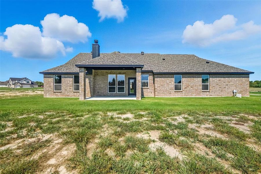 Back of house featuring brick siding, a patio, and a lawn Back of house featuring brick siding, a patio, and a lawn