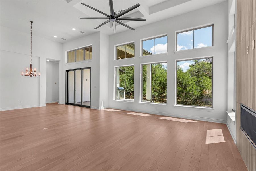 Natural light floods this great room, highlighting soaring ceilings and elegant wood flooring.