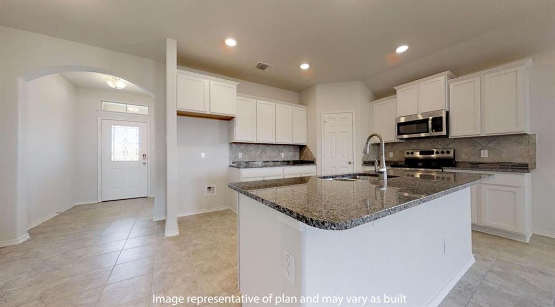 Kitchen featuring white cabinets, dark stone countertops, backsplash, appliances with stainless steel finishes, and arched walkways Kitchen featuring white cabinets, dark stone countertops, backsplash, appliances with stainless steel finishes, and arched walkways