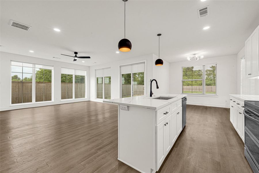 The open-concept layout makes the kitchen ideal for both everyday living and entertaining, offering seamless flow into the surrounding living and dinning areas. Expansive windows surround the space, filling the room with natural light while showcasing views of the fully fenced backyard area.