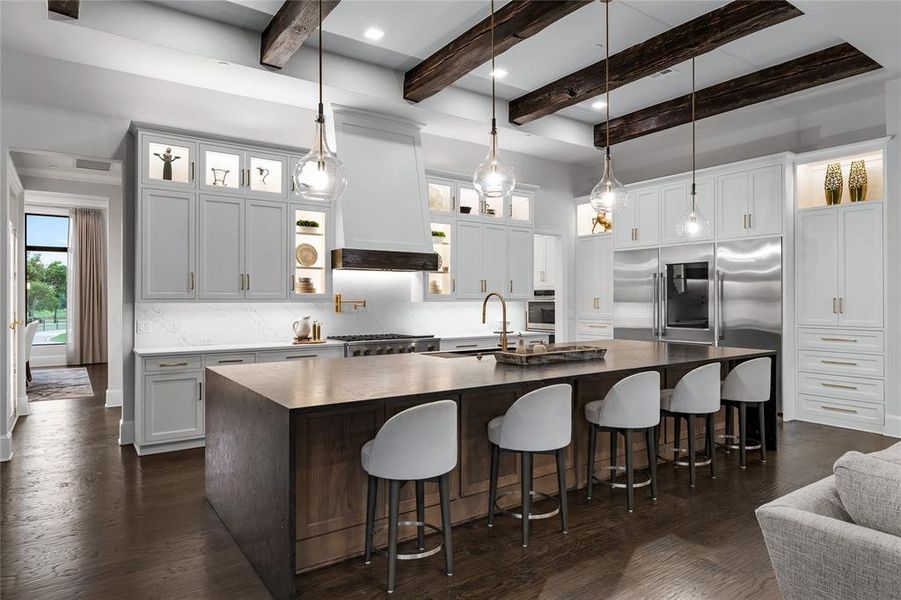 Kitchen with white cabinets, sink, backsplash, and a large island with sink