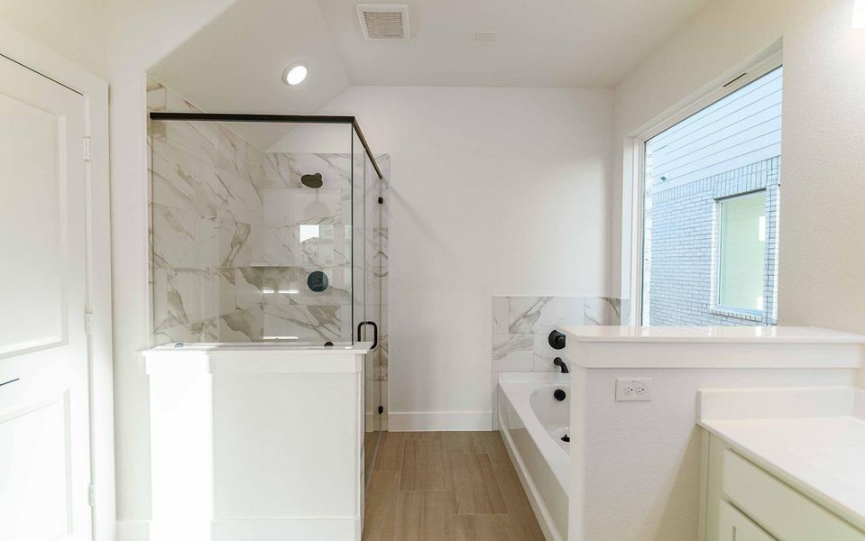 Bathroom with a garden tub, a marble finish shower, and vanity