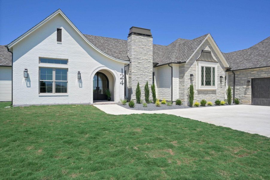 View of front of house featuring a front yard, a garage, a chimney, and concrete driveway