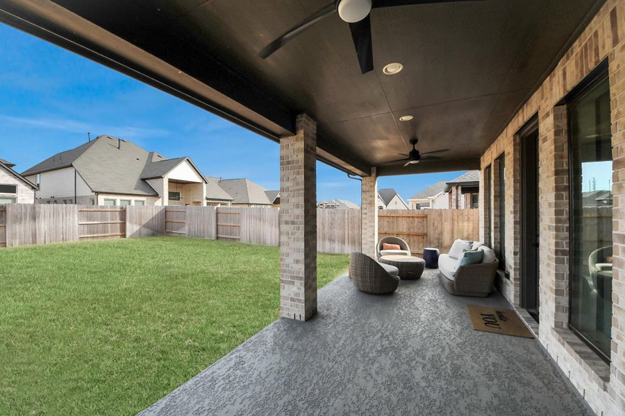 Spacious covered patio overlooking fenced yard, ideal for relaxing or entertaining.
