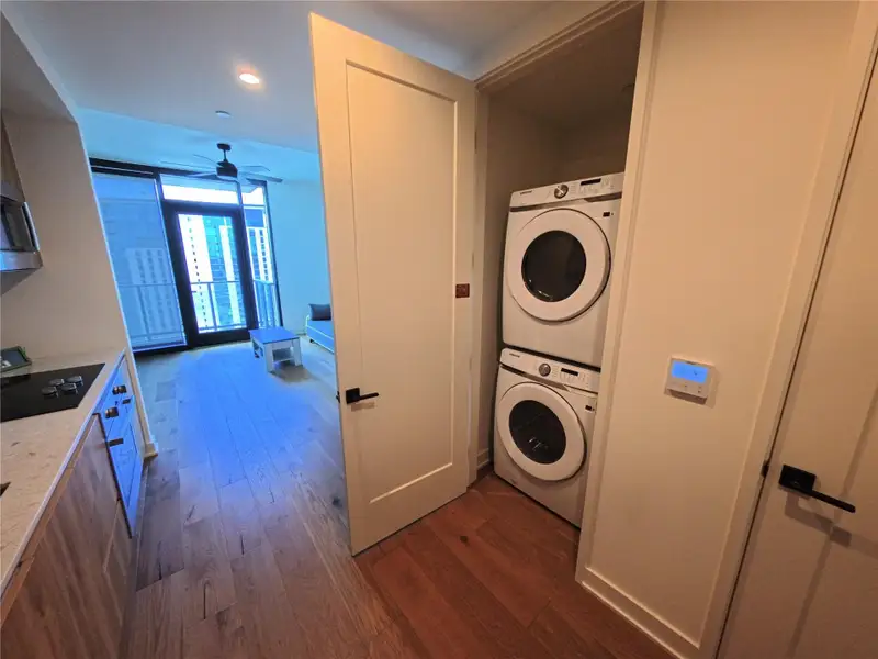 Laundry area featuring stacked washer and clothes dryer, dark wood-style flooring, ceiling fan, and recessed lighting Laundry area featuring stacked washer and clothes dryer, dark wood-style flooring, ceiling fan, and recessed lighting