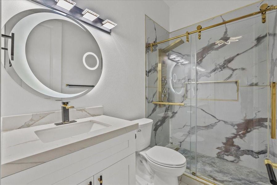 Stylish en-suite  secondary bath in second downstairs bedroom with marble-look finishes and gold accents