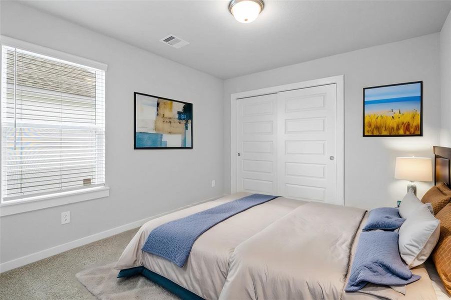 Secondary bedroom features plush carpet, neutral paint, lighting and a large window with privacy blinds.