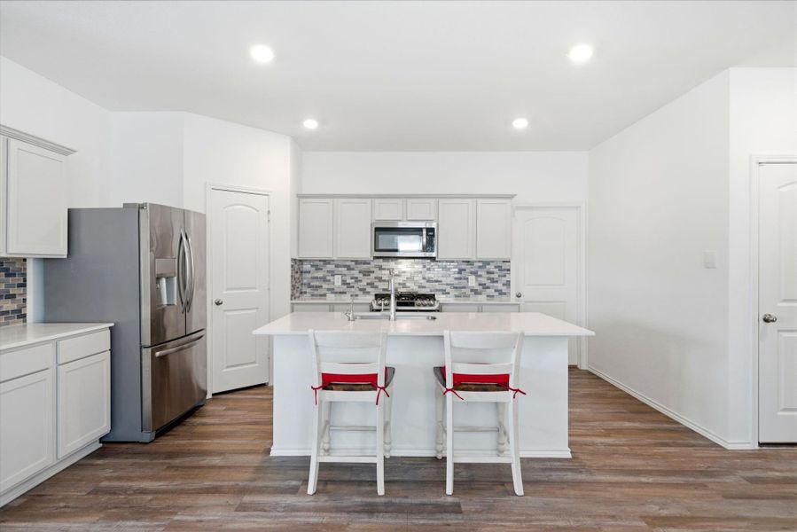 Center-stage quartz island with a breakfast bar, ideal for quick bites and family mornings.
