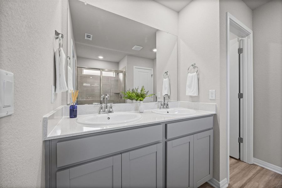 Double vanities with stone counters flank sleek cabinetry above durable wood-look flooring.