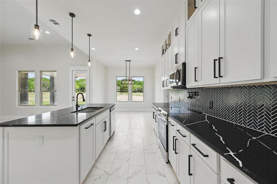 Kitchen with appliances with stainless steel finishes, a sink, light marble finish flooring, recessed lighting, and tasteful backsplash Kitchen with appliances with stainless steel finishes, a sink, light marble finish flooring, recessed lighting, and tasteful backsplash