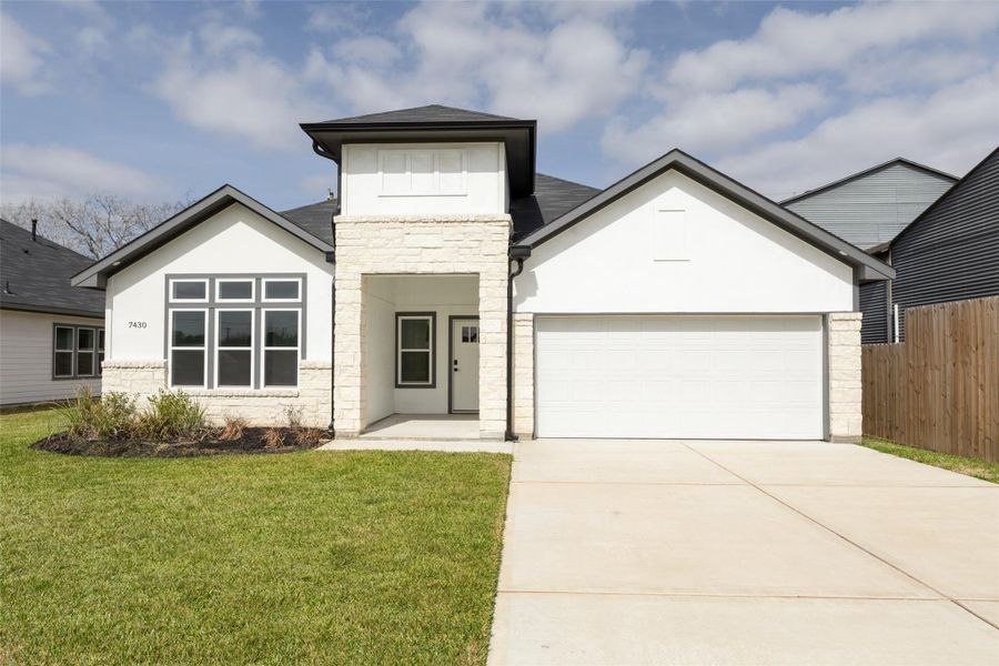 Modern home features an inviting entrance with a combination of stone and siding, a garage, and a well-maintained lawn. Modern home features an inviting entrance with a combination of stone and siding, a garage, and a well-maintained lawn.