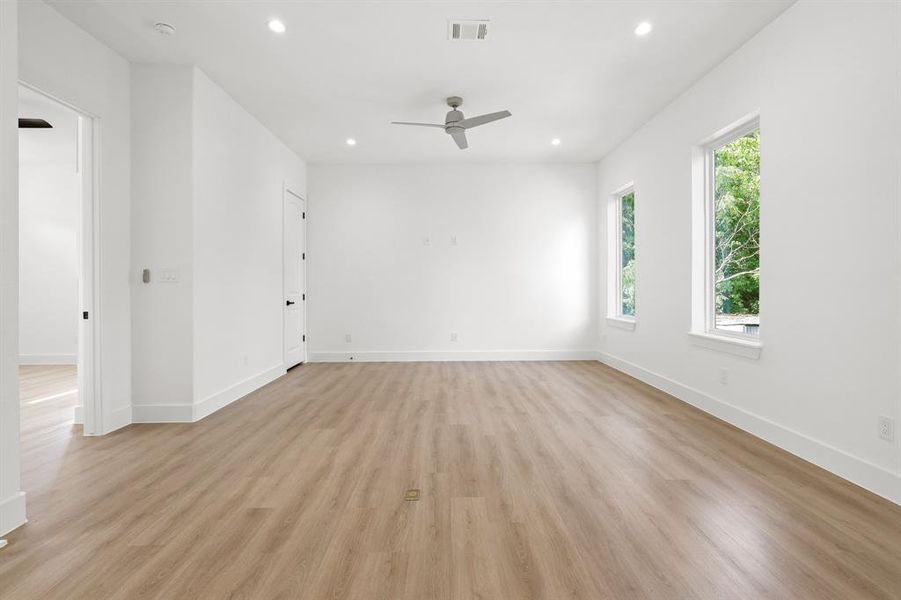 Empty room featuring ceiling fan, light wood-type flooring, and a wealth of natural light