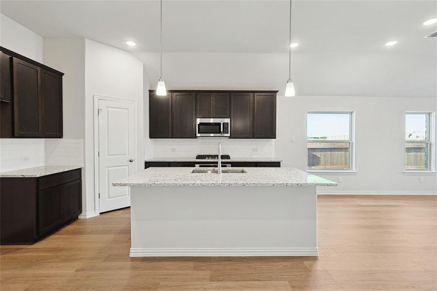 Kitchen with light hardwood / wood-style floors, a healthy amount of sunlight, and decorative backsplash