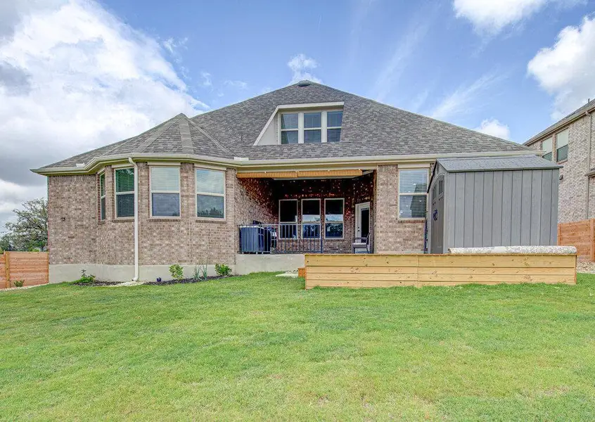 Classical brick architecture anchors this rear facade featuring a covered patio and grassy yard. Classical brick architecture anchors this rear facade featuring a covered patio and grassy yard.