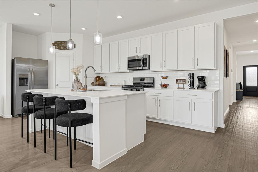 Sleek modern kitchen featuring white cabinetry, stainless steel appliances, and a spacious island with stylish pendant lighting and seating. Sleek modern kitchen featuring white cabinetry, stainless steel appliances, and a spacious island with stylish pendant lighting and seating.