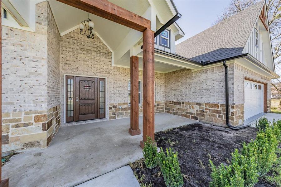 Property entrance with stone siding, a shingled roof, and brick siding