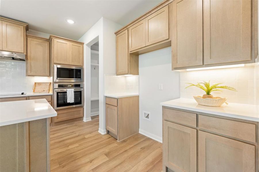 Kitchen featuring light brown cabinets, appliances with stainless steel finishes, tasteful backsplash, light wood-style floors, and recessed lighting