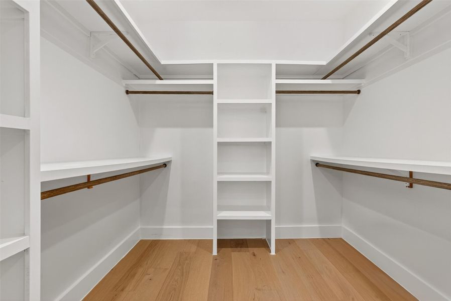 Spacious closet featuring wood floors, built-in shelving and plenty of hanging space Spacious closet featuring wood floors, built-in shelving and plenty of hanging space