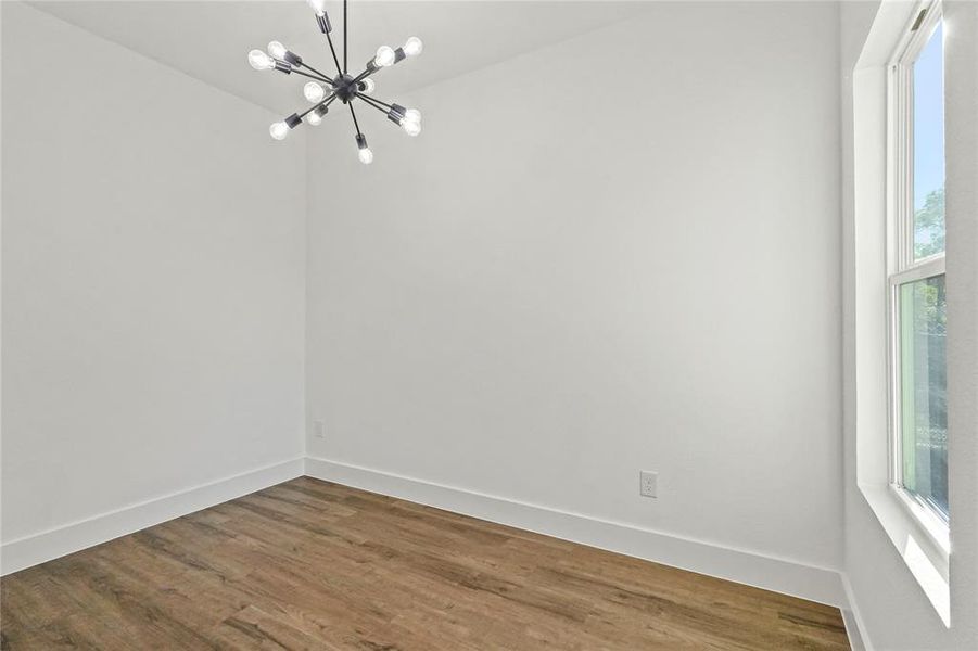 Unfurnished room with wood finished floors and a chandelier
