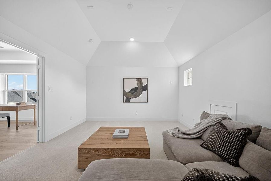 Carpeted living room with baseboards and vaulted ceiling Carpeted living room with baseboards and vaulted ceiling